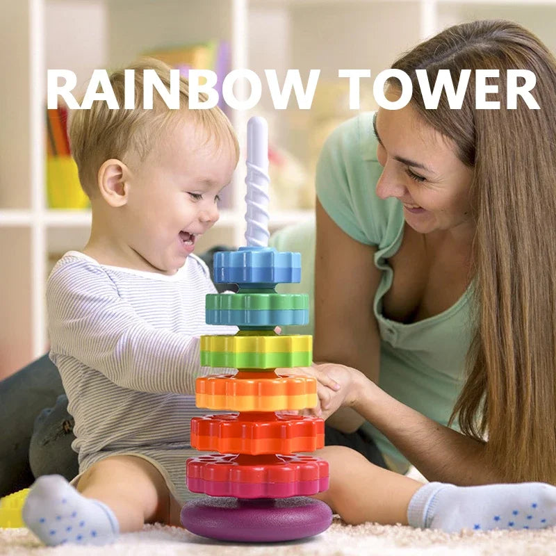 A young girl is playing with a colorful rainbow tower stacking toy on the floor.