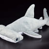 A soft gray hammerhead shark plush toy lying on a dark surface.