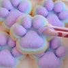 A close-up of a soft purple and blue cat paw squishy fidget toy made of mochi-like foam.