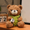 A brown teddy bear plush toy wearing a lime green shirt and holding a soccer ball.