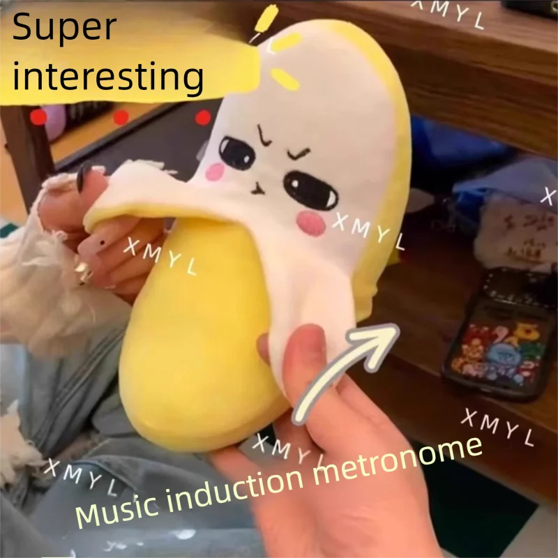 A hand is holding a yellow, fruit-shaped plush toy with a mouth opening, demonstrating its music induction function.