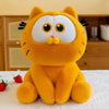 An orange Garfield plush doll with large eyes and pink nose sitting on a white surface.