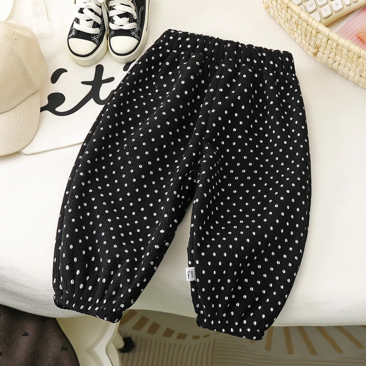 Black fleece-lined pants with white polka dots laid flat on a white surface.