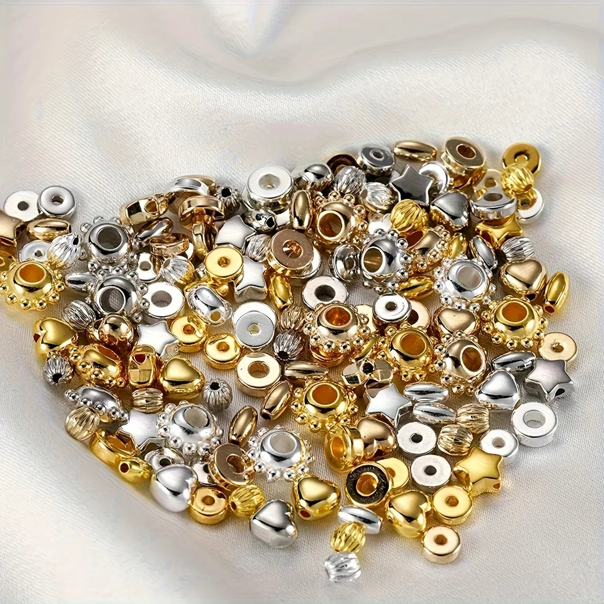 A pile of mixed color acrylic spacer beads in gold silver and clear tones for jewelry making
