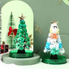 A festive crystal growing tree decoration featuring green and white crystals on a dark base.
