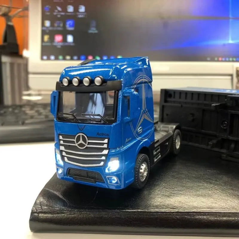 A blue Mercedes Actros diecast container truck with pull-back action displayed on a black surface.
