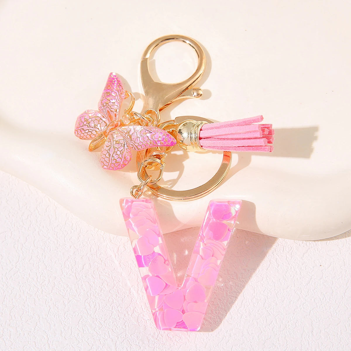 Gold initial heart keychain featuring a pink butterfly charm and a pink acrylic V-shaped charm