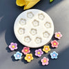 A white silicone mold with multiple daisy flower shapes is shown alongside several small, colorful fondant flowers.