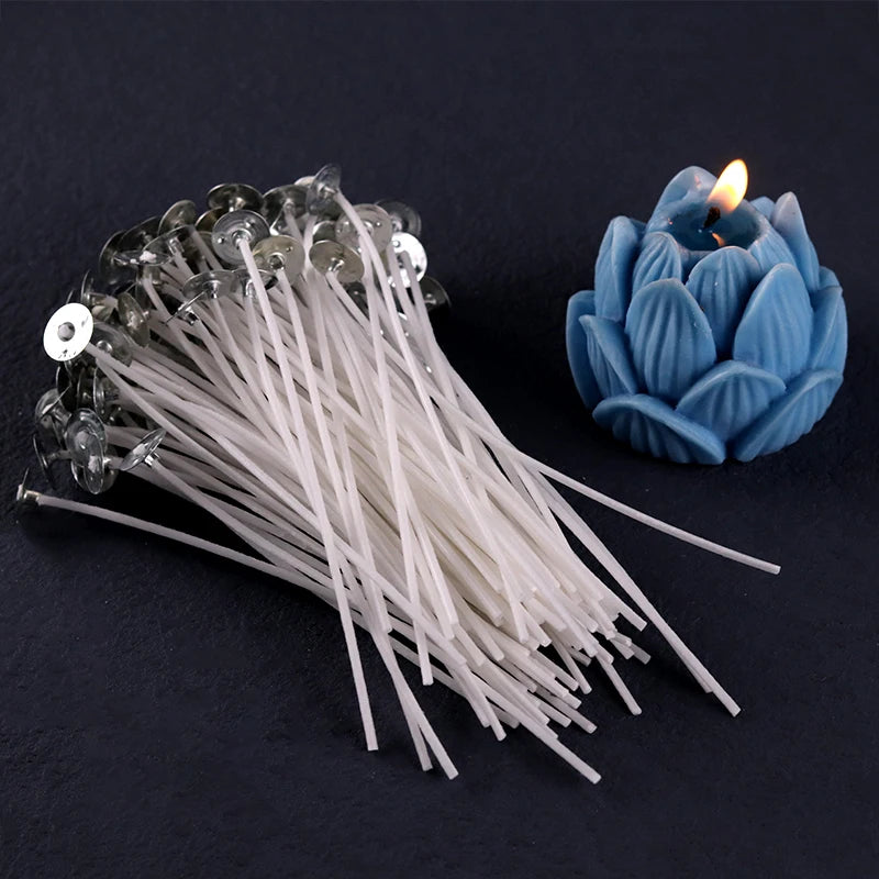 A bundle of white cotton candle wicks with metal sustainers next to a blue candle.
