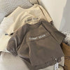 A stack of light brown and gray short-sleeve t-shirts featuring a printed gummy bear design.