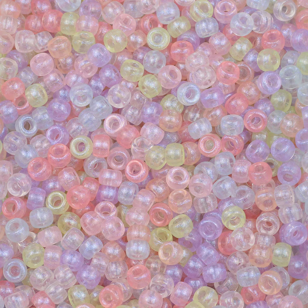 A close-up view of small, solid color pony beads in various shades of pink, purple, and yellow.