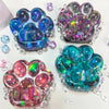 A collection of iridescent, purple, and blue cat paw squishy fidget toys with sparkling accents.