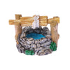 A miniature figurine of a rustic stone well with wooden beams and green foliage.