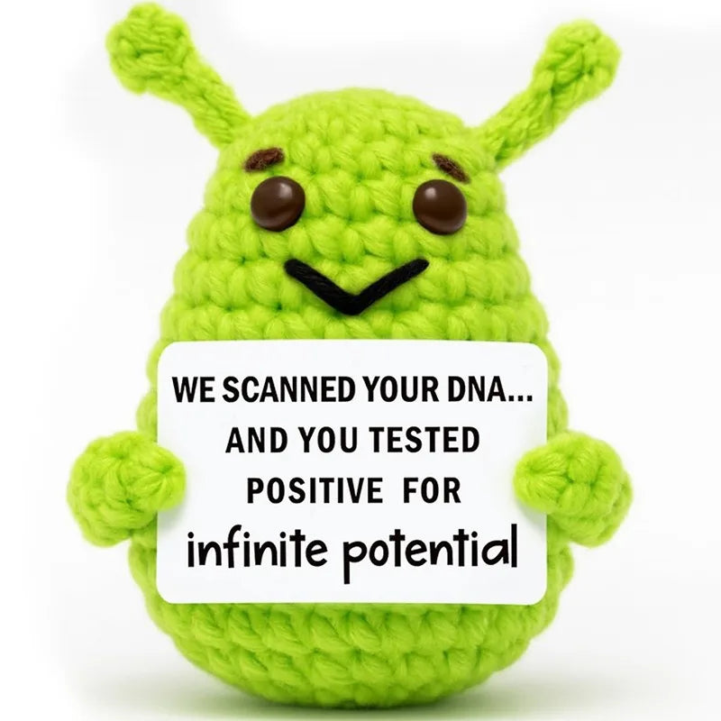 Handmade crochet alien plush toy in lime green with embroidered eyes and a positive message tag