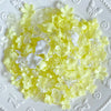 A pile of yellow and white acrylic bow and flower beads for DIY jewelry making