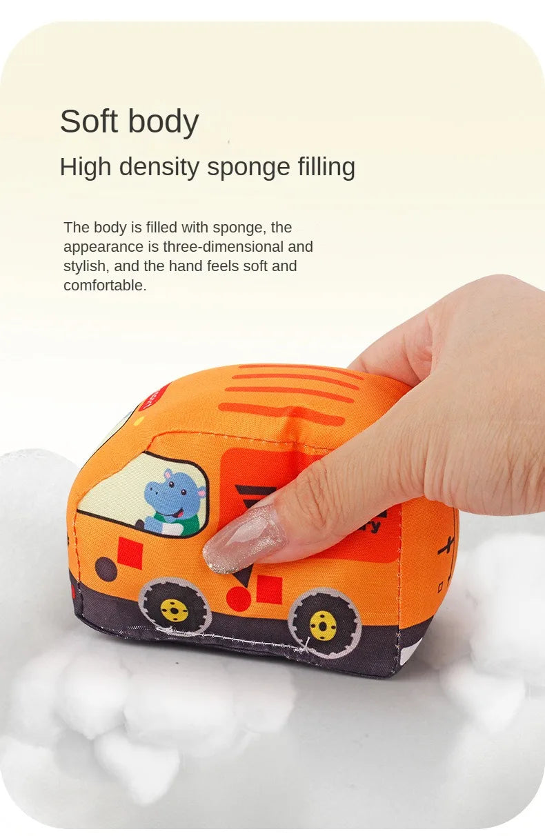 An orange fabric car toy with a map game mat is being held by a hand, showing its soft texture.