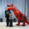 A person is posing with an inflatable T-Rex costume for adults in a studio setting.