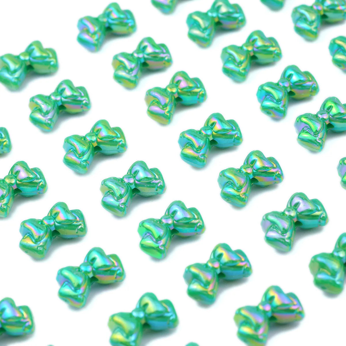 A collection of iridescent green acrylic bow beads used for jewelry making.