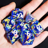A hand holds a set of blue resin polyhedral dice on a dark background.