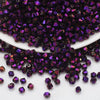 A pile of small, faceted purple and magenta crystal beads used for jewelry making.