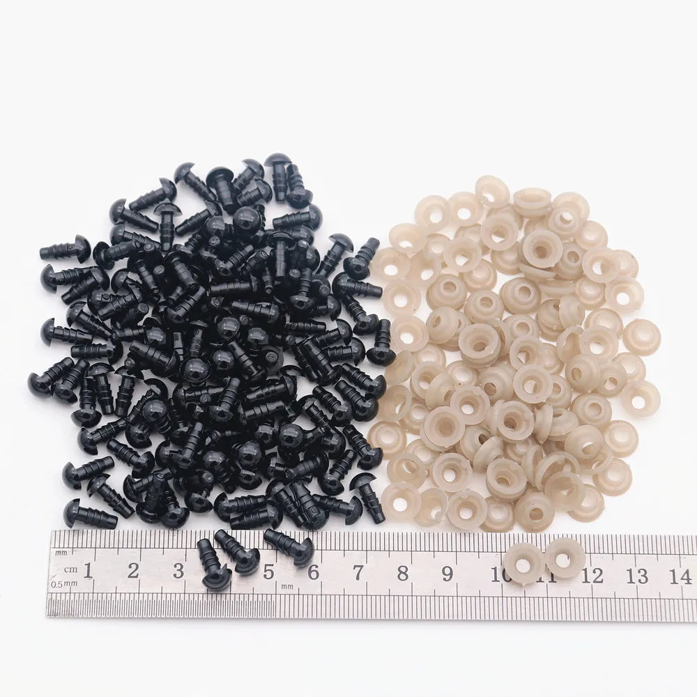 A collection of black and beige plastic safety eyes for amigurumi, displayed next to a ruler.