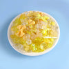 A mix of yellow and clear acrylic beads for DIY jewelry making displayed on a white plate.