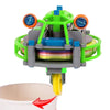A green and blue gyroscopic unicycle fingertip spinner device with a yellow blade is shown above a white cup.