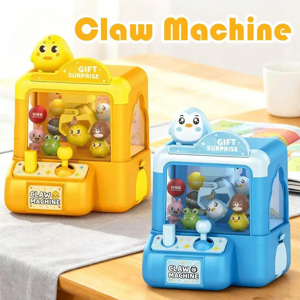 A yellow and blue mini claw machine toy for kids with a gift surprise feature displayed on a wooden surface.