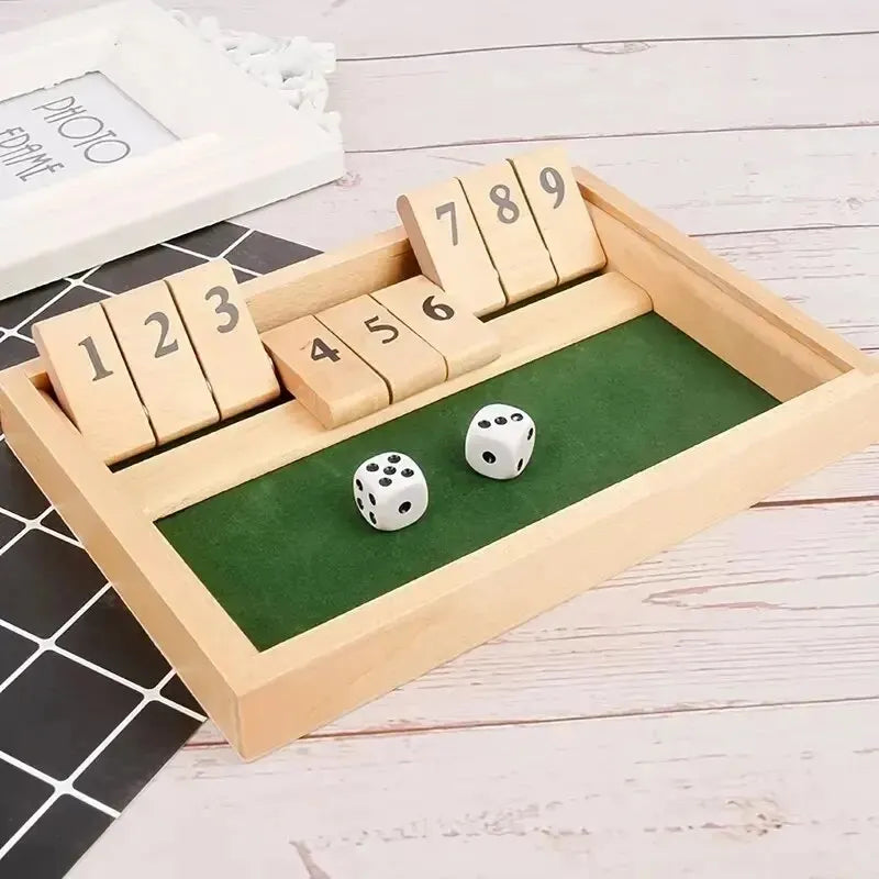 A wooden shut the box dice game box with numbered dice and a green felt playing area.