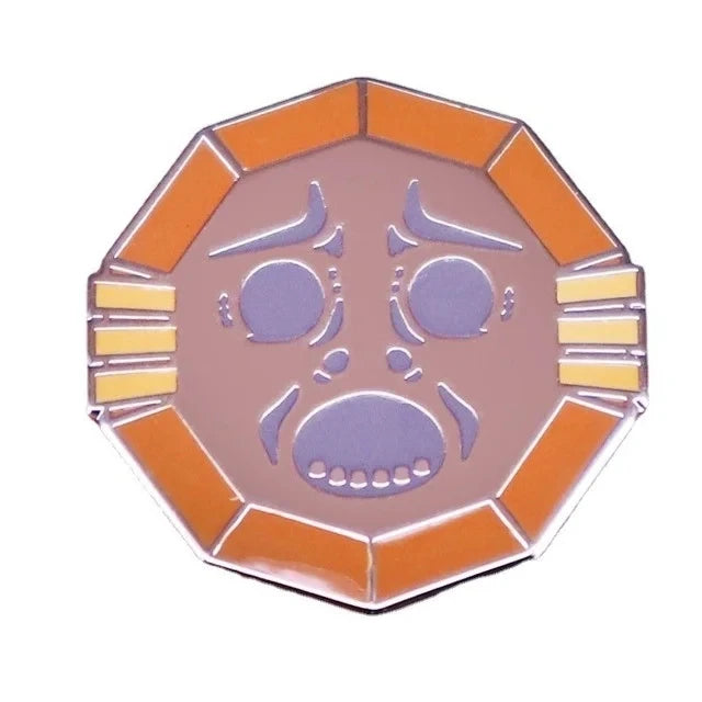 A hexagonal enamel pin featuring a stylized cartoon face with purple eyes and mouth, set in an orange border.