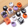 A collection of Halloween themed acrylic beads in black, orange, and purple on a wooden surface.