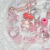 A collection of mixed pink and clear acrylic bow and flower beads for jewelry making.