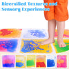 A child's feet are shown interacting with a colorful liquid sensory play mat featuring various textures and colors.