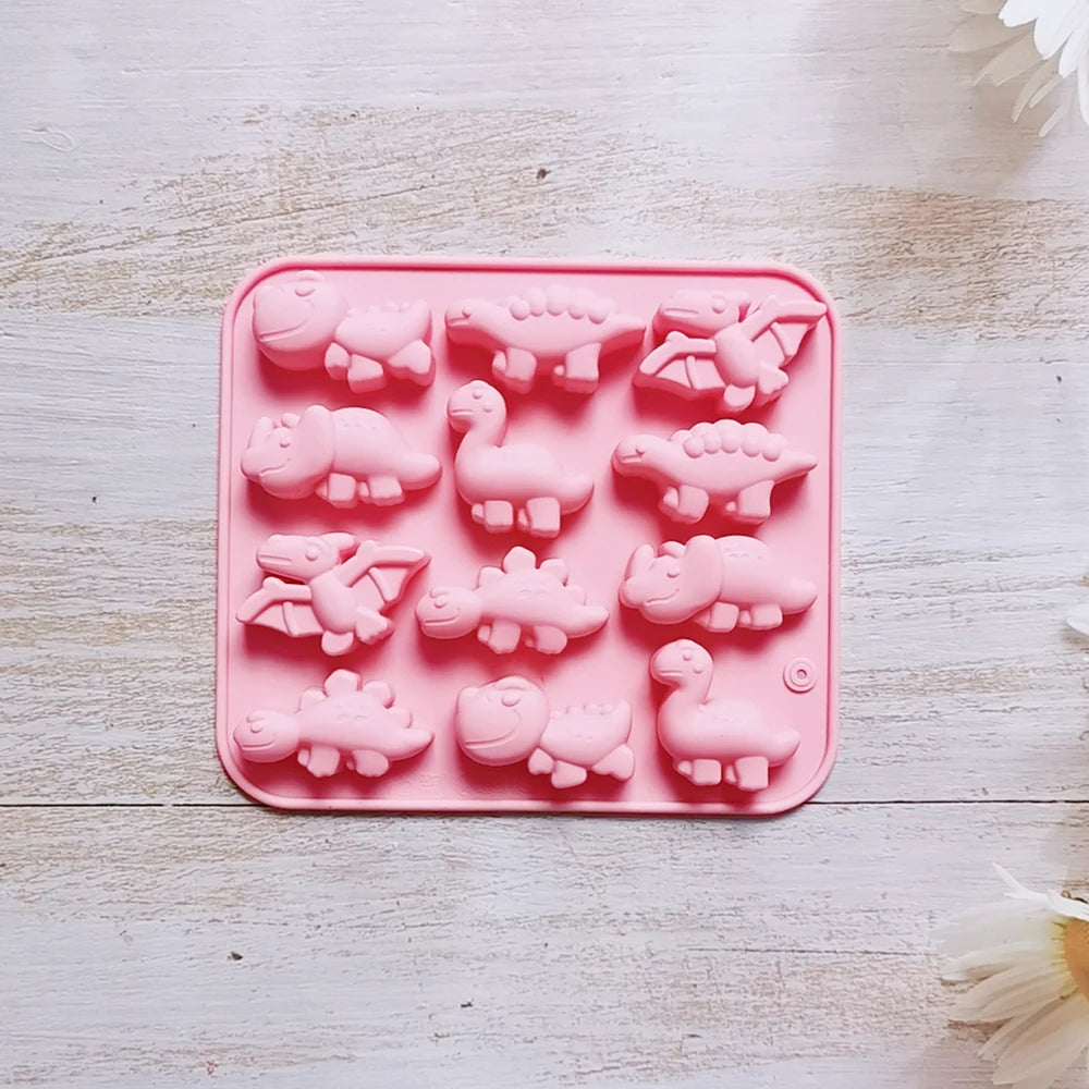 A pink silicone mold with various dinosaur shapes for baking, chocolate, and craft projects.