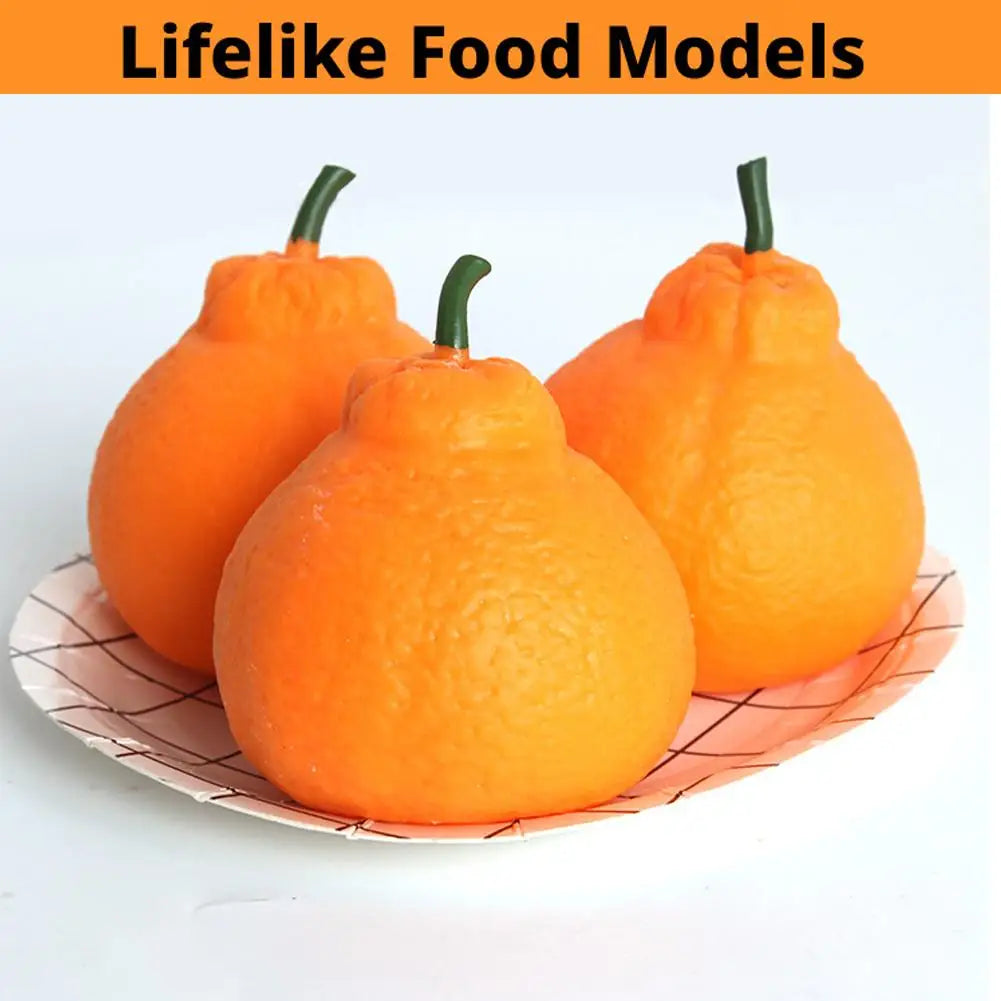 Three realistic orange fruit models resembling small pumpkins or squashes displayed on a paper surface.