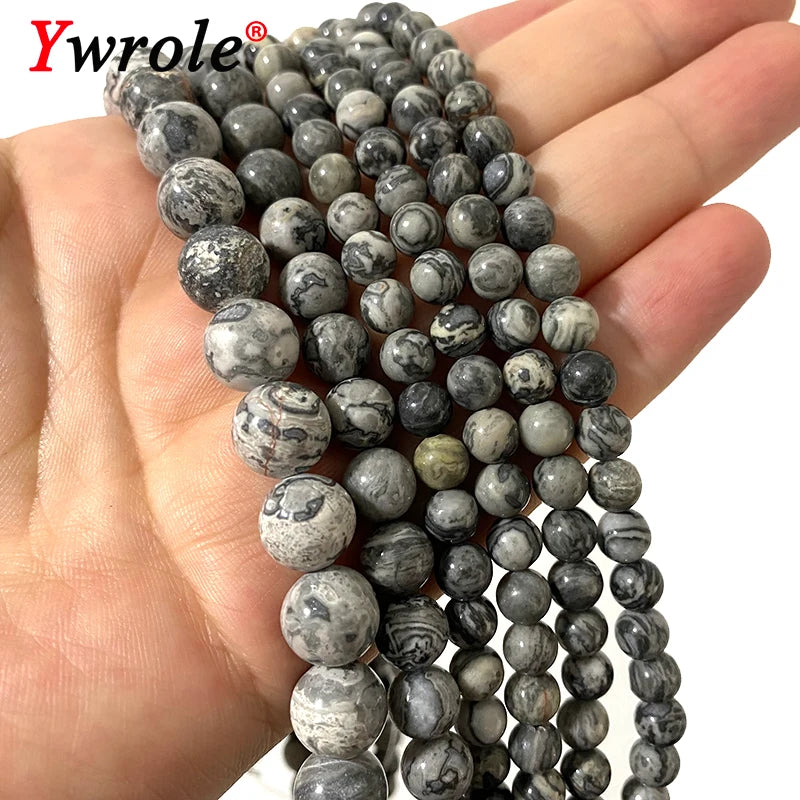 A hand holds a strand of natural map jasper loose beads for jewelry making