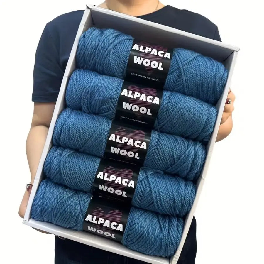 A box containing a 5-pack of blue alpaca wool yarn skeins for knitting and crochet.
