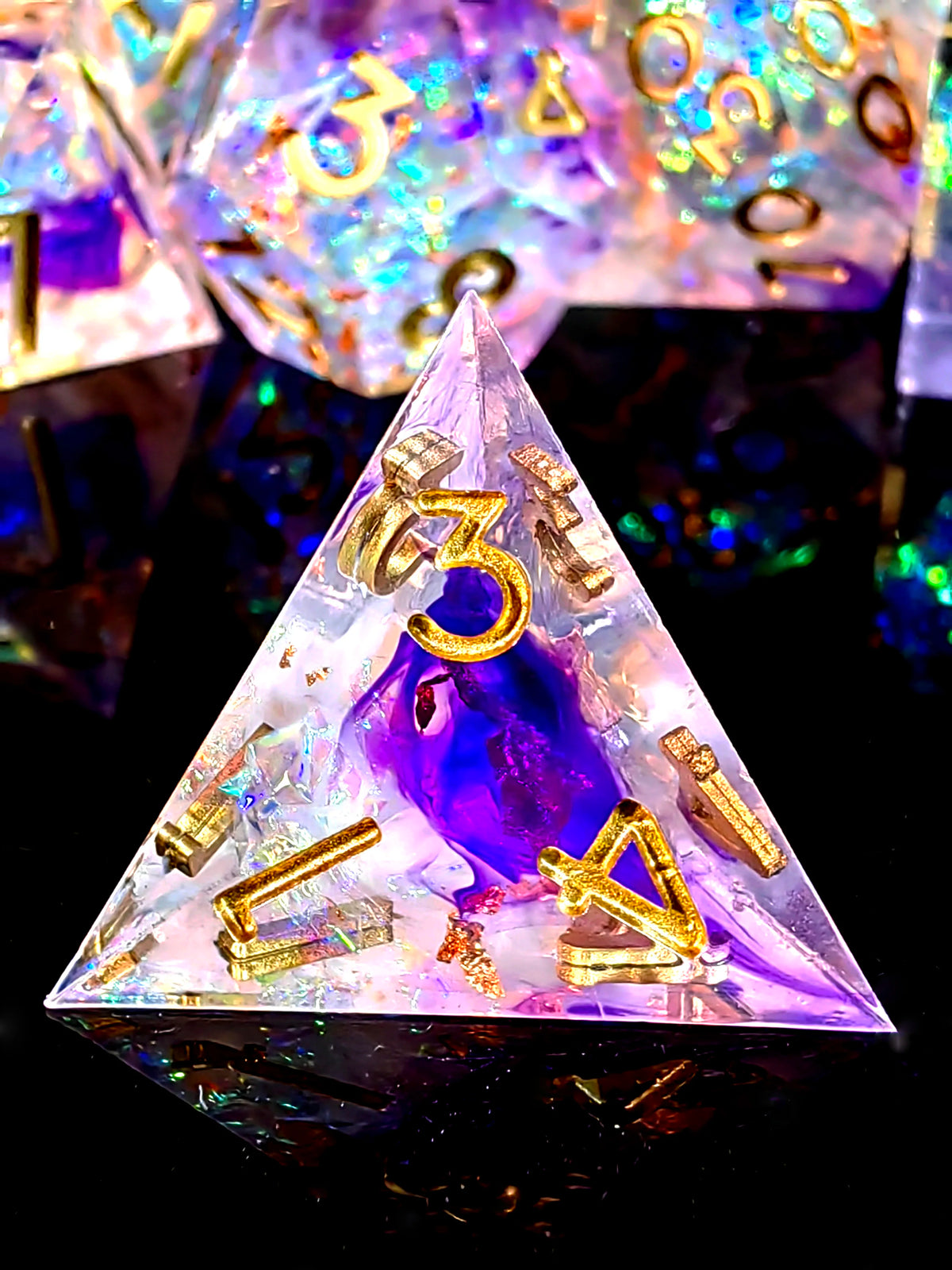 A handcrafted resin dodecahedron die set with light purple and gold numbers resting on a reflective surface.