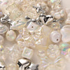 A close-up of various iridescent and silver acrylic bow and flower beads for DIY jewelry making.
