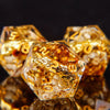 A close-up of a set of resin dice with golden elven numbers, resting on a dark surface.