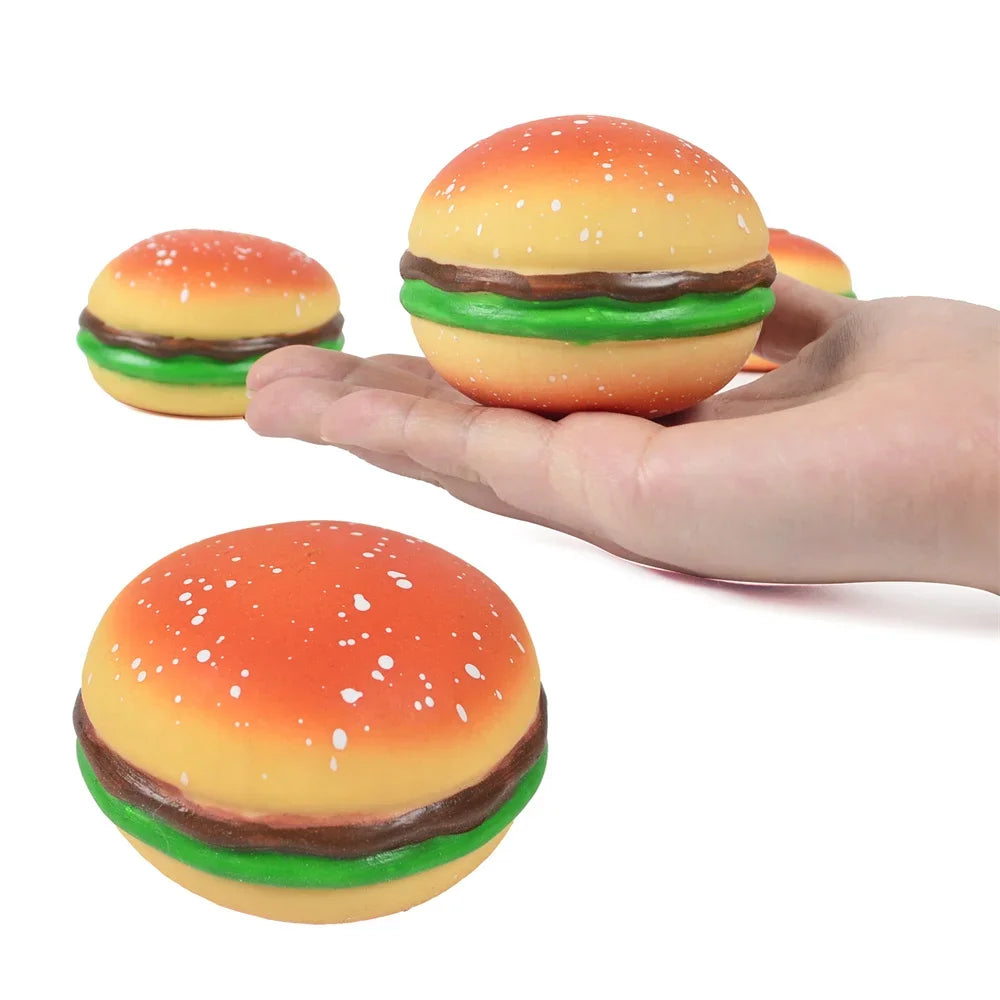 A hand holds a squishy hamburger stress ball with a bright orange top and green bun.