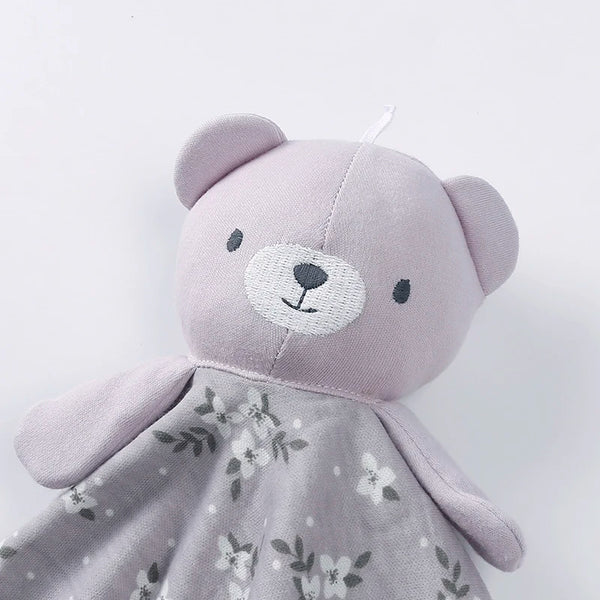 A soft, light purple teddy bear stuffed animal with a floral print dress.