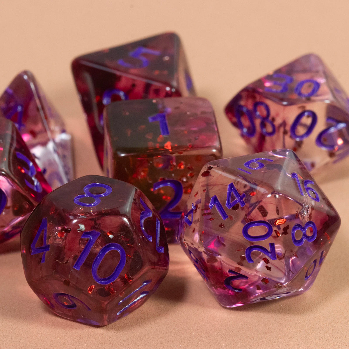 A collection of glitter polyhedral dice including a D4, D6, D8, D10, D12, and D20, scattered on a light surface.