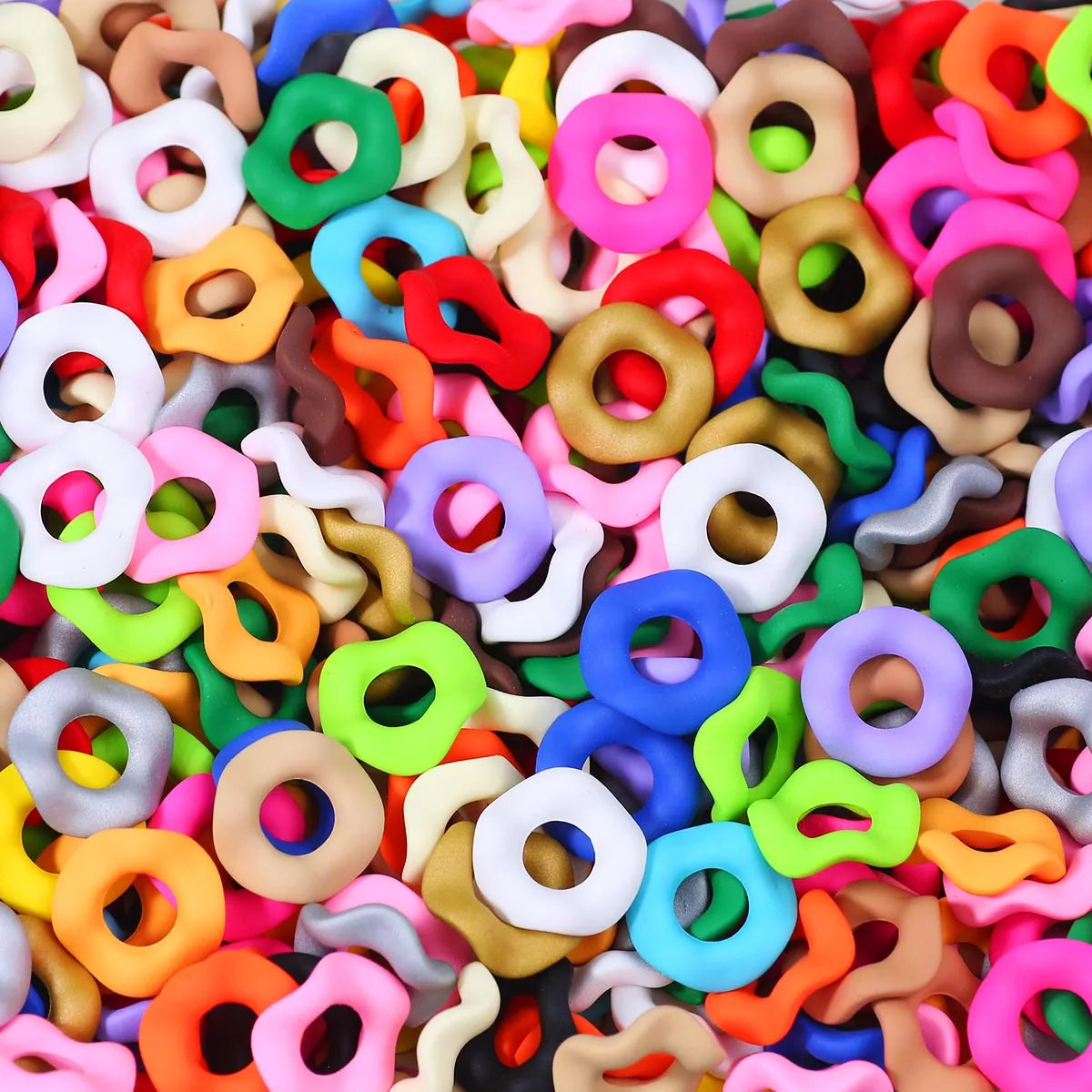 A close-up view of numerous colorful, wave-patterned acrylic beads in various shades of pink, green, yellow, and orange.