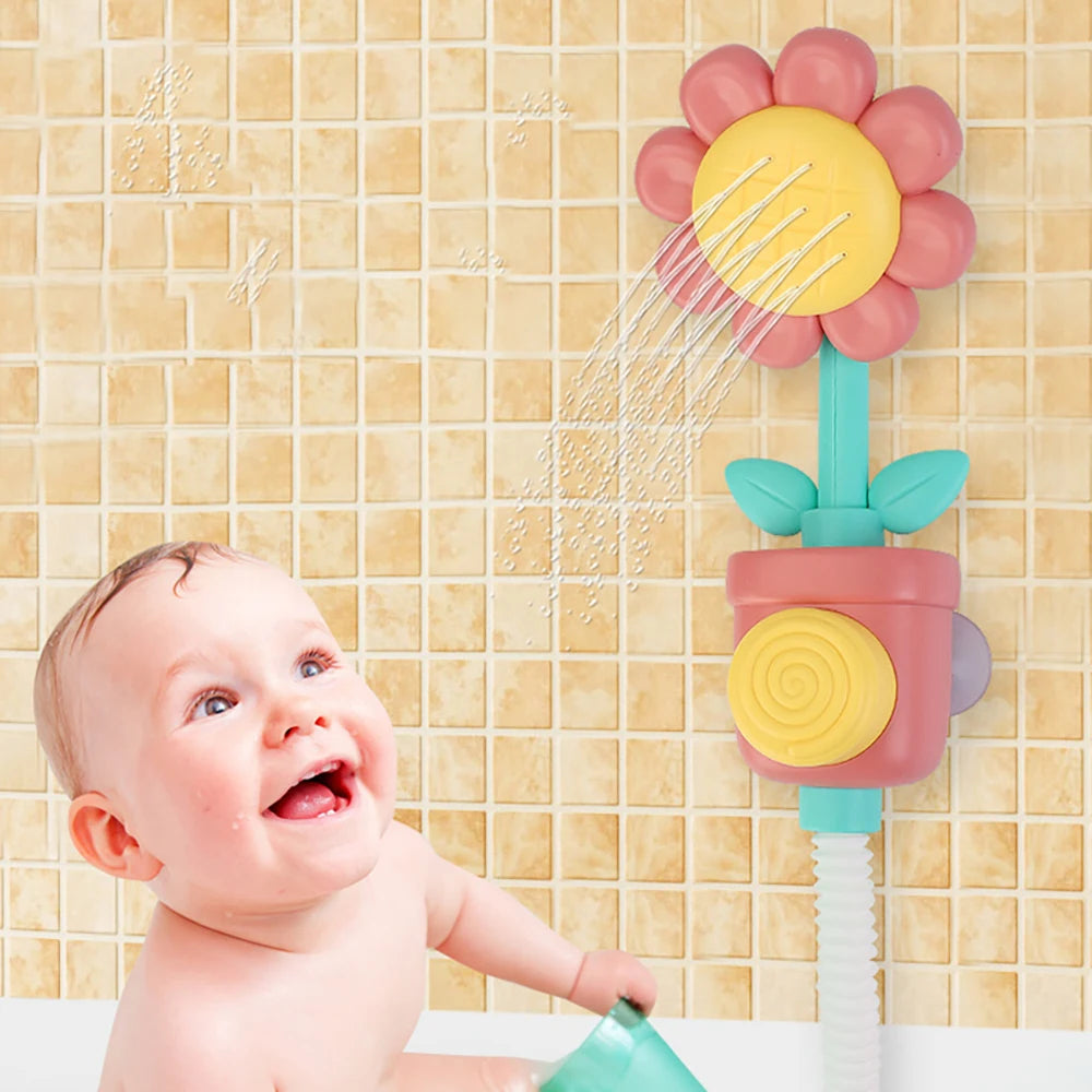 A baby is interacting with a pink and yellow sunflower bath shower sprinkler toy against a light tiled background.