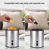 A close-up of a silver electric heater designed for wax melts and essential oils, shown next to wax and oil containers.