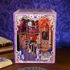 A purple box containing a tarot deck and accessories with LED lighting, next to a stack of books.
