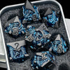A set of black metal dice featuring a dragon design are displayed in a silver container.