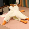 A white plush goose pillow with orange feet lying on a pink surface.