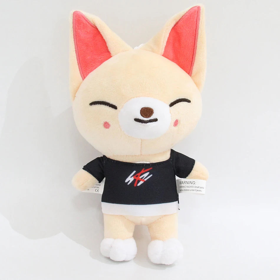 A light beige cartoon fox plush toy with pink ears and a black shirt.